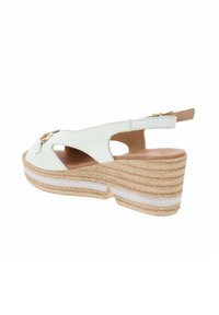 Sandalo con zeppa in pelle bianca con lati intagliati, suola beige e tacco in corda intrecciata. Presenta una fibbia in tonalità oro e una striscia bianca texturizzata.