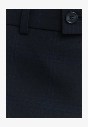 Granatowa krata z drobnym wzorem, o gładkiej fakturze i z detalem zapięcia na guzik. Odpowiednia do spodni szytych na miarę.
