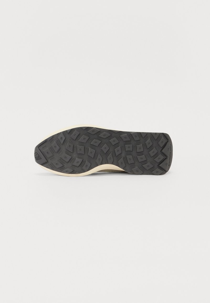 Semelle de chaussure en caoutchouc noir avec un motif texturé, dotée d'un intercalaire beige. Le design inclut des formes géométriques pour l'adhérence.