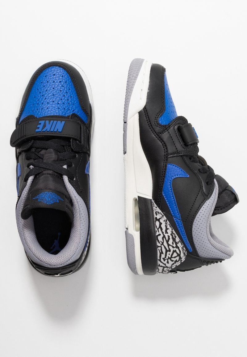 Paire de baskets Nike noires, bleues, grises et blanches avec fermeture Velcro, lacets et détail à motif au talon, vues de dessus et de côté.