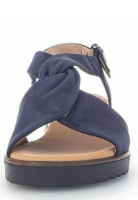 Navyblaue Sandalen mit einem geknoteten Riemendesign, das eine glatte Textur, offene Zehen und eine kontrastierende, leichte Sohle aufweist. Verstellbarer Knöchelriemen.