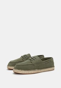 Zelene platnene cipele s okruglim prstom, vezanjem i potplatima od jute u espadril stilu. Imaju metalne rupice za vezivanje i šivane detalje.