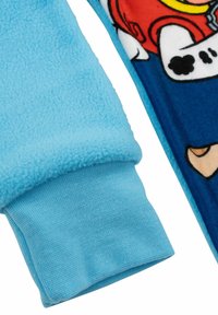 Maglia da pigiama in pile con tessuto blu caratterizzato da una morbida texture, polsino in blu chiaro e design di sfondo blu con dettagli di personaggi.