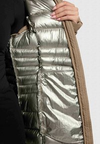 Kurtka puchowa z wewnętrzną warstwą w metalicznym srebrze i beżową powłoką. Teksturowana izolacja z poziomymi przeszyciami. Zawiera kieszeń boczną.