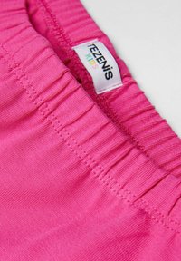 Shorts pour enfants rose en tissu doux avec une taille élastique. Présente un fin côtelage et une étiquette avec le nom de la marque "Tezenis."