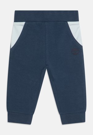 Marineblauwe peuterbroek met lichtblauwe zijzakken, elastische tailleband, geribbelde boorden en een subtiel donker logo op het rechterbeen.