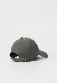 Casquette de baseball en coton gris avec une visière courbée, une sangle ajustable et une boucle métallique contrastante à l'arrière. Texture lisse, design simple.
