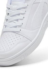 Baskets blanches avec un dessus en cuir texturé, un bout rond, des détails perforés, des lacets blancs et une semelle en caoutchouc avec un motif de traction.
