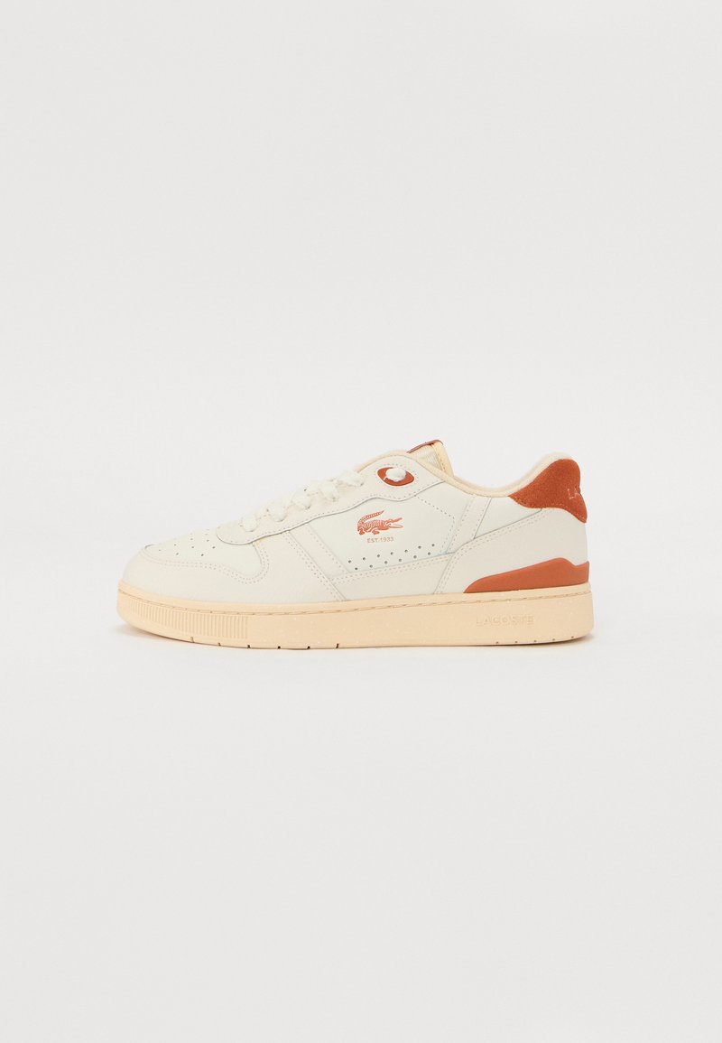Sneaker in pelle bianca con suola beige chiaro e accenti arancioni. Presenta punta arrotondata, chiusura con lacci e dettaglio del logo di lato.