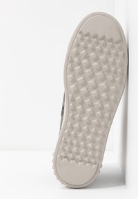 Podešev boty s texturovaným gumovým povrchem s diamantovými vzory v světlé béžové barvě; strana má textilní složení s texturou.