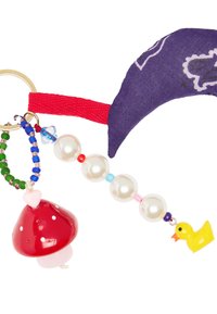 Breloczek z zawieszką w kształcie czerwonego grzyba, białymi perłami, zawieszką w kształcie żółtej kaczki oraz fioletowym materiałowym akcentem na czerwonym pasku.