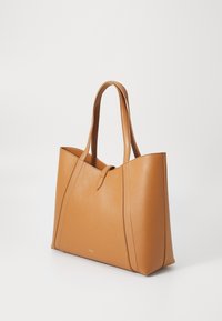 Sac fourre-tout en cuir tan avec une texture lisse, deux poignées robustes et un design minimaliste. Doté d'un logo en relief à la base.