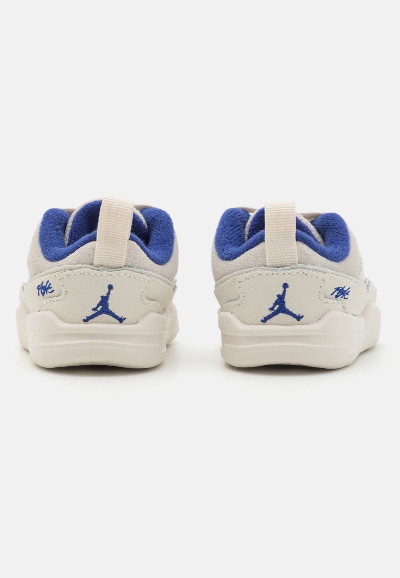 Zapatillas blancas y azules con parte superior de ante y tejido, que incluyen una puntera, un tirador en el talón y un logotipo bordado en la parte trasera.