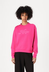 Felpa fucsia con scollo rotondo e spalle scese. Presenta il logo "Hugo" in una tonalità più chiara sul petto. Tessuto morbido.