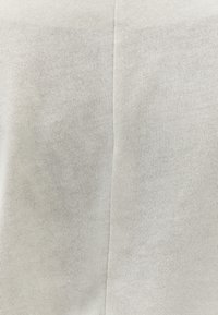 Nahaufnahme eines hellgrauen, gerippten Stoffes mit einer vertikalen Naht in der Mitte.