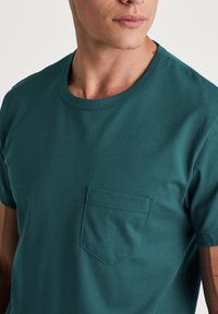 Teal kortemouwen T-shirt van katoen, met een ronde hals en een linkerkantzakje met een subtiele gestikte rand.