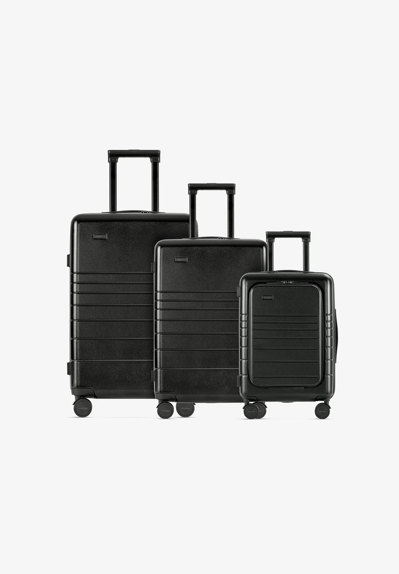 Zwarte drie-delige kofferset: harde schaal, gestructureerde afwerking, horizontale groeven, uitschuifbare handgreep, 360-graden draaibare wielen.