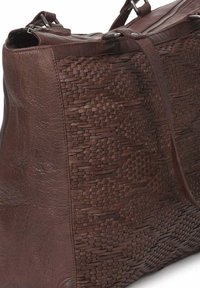 Bolso de mano de cuero marrón con panel frontal texturizado trenzado, doble asa y cierre de cremallera.