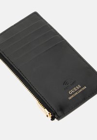 Portefeuille en cuir véritable noir avec fermeture éclair dorée, comportant six fentes pour cartes et un logo en relief. Texture lisse, design minimaliste.
