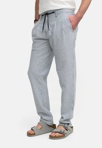 Lette, stribede bukser i blå og hvid med elastisk talje og snøredetalje. Bæres med grå sandaler.