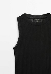 Haut noir sans manches en maille côtelée avec encolure ronde, mettant en avant la partie supérieure du torse, posé à plat sur un fond blanc.