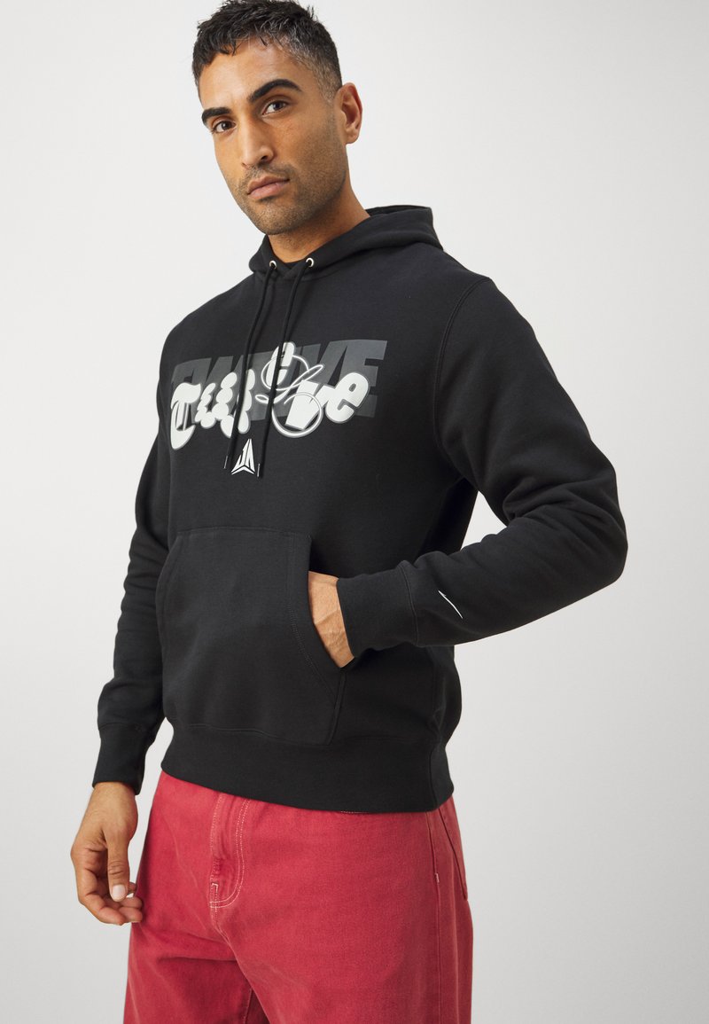 Czarna bluza z kapturem z przednią kieszenią, z wyraźnym, białym i szarym nadrukiem. Materiał bawełniany, ze ściągaczami na mankietach i u dołu.