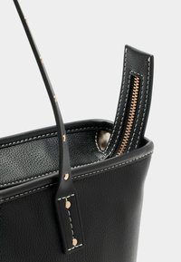 Fekete bőr bevásárlótáska texturált felülettel, arany cipzárral és varrási részletekkel. Fogantyúk fém szegecsekkel díszítve.