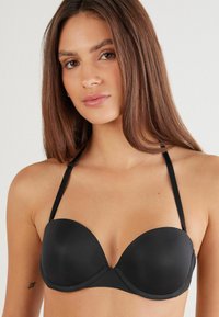 Sort, polstret push-up-bh lavet af glat materiale. Har justerbare stropper og et sømløst design med en buet bøjle for støtte.