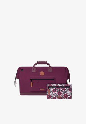Le sac de sport bordeaux présente une surface texturée, des accents en cuir, des compartiments zippés et une pochette détachable à motif floral.