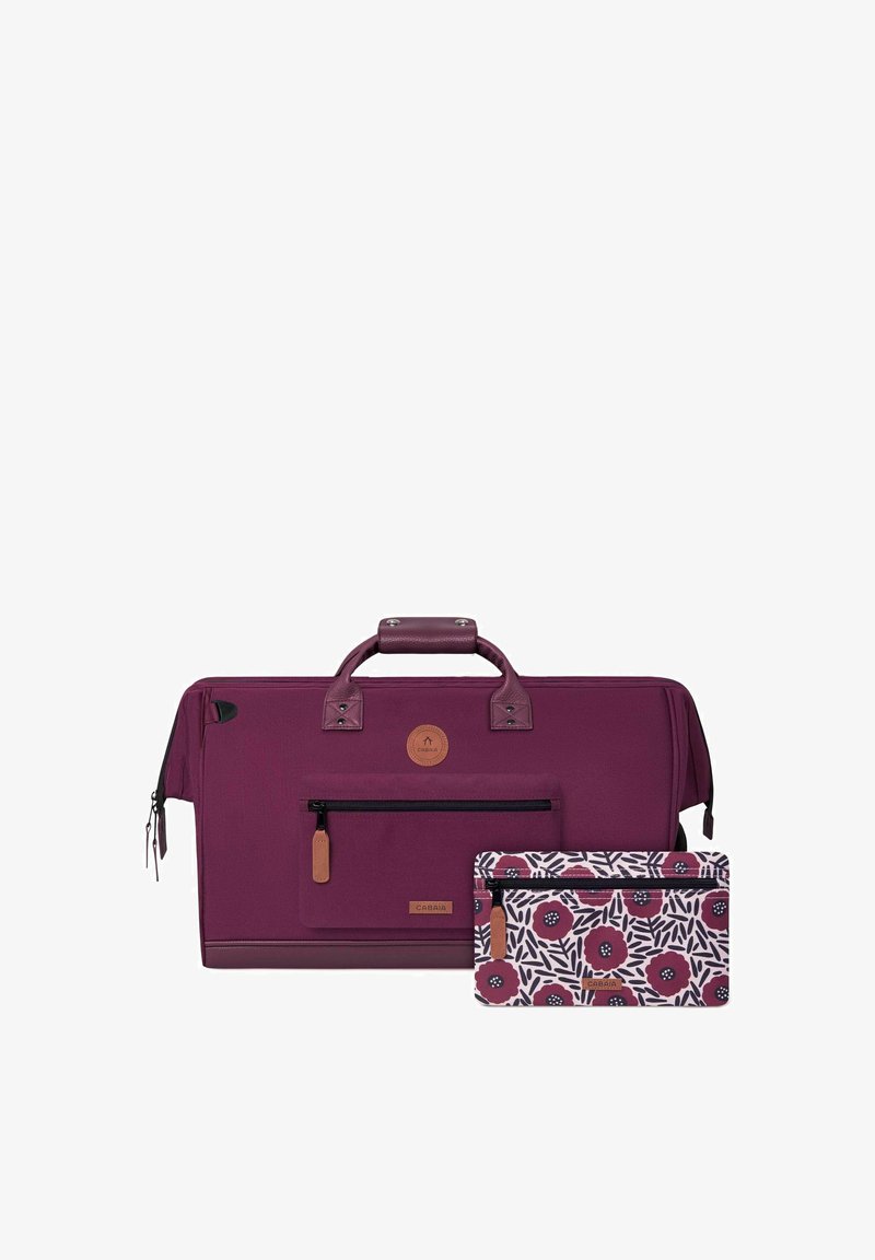 Le sac de sport bordeaux présente une surface texturée, des accents en cuir, des compartiments zippés et une pochette détachable à motif floral.