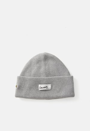 Graue Strickmütze mit umgeschlagenem Saum, ausgestattet mit einem strukturierten Rippmuster und einem aufgenähten Lacoste-Label auf der Vorderseite.