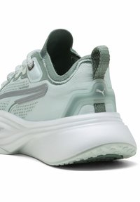 Zapatilla deportiva verde claro con una parte superior de malla texturizada, media suela blanca, collar acolchado y acentos reflectantes. Logo en el talón y la lengüeta.