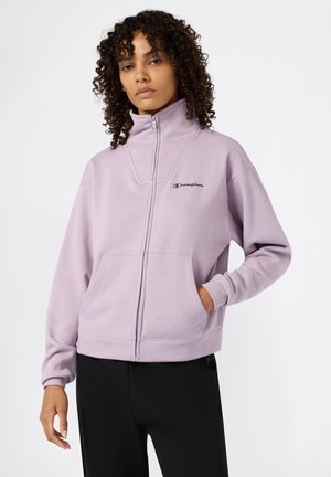 Felpa zip con collo alto di un delicato colore viola, dotata di tasche frontali e logo ricamato. Presenta una texture morbida e una vestibilità comoda.