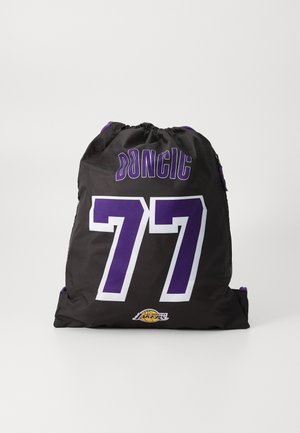 Black drawstring bag featuring white "77" and "DONCIC" in purple, with a Lakers logo at the bottom. Made of durable fabric.