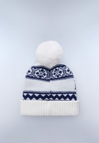 Cappello di maglia in navy e bianco con motivi geometrici, un risvolto bianco a coste e un grande pompon in pelliccia sintetica bianca sulla parte superiore.