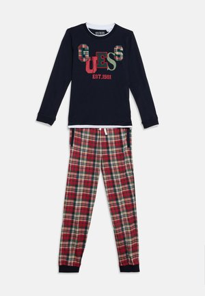 Haut à manches longues bleu marine avec logo "GUESS" et texte "EST. 1981", assorti à un pantalon de pyjama à carreaux rouge, beige et vert.