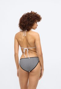 Bikini med svart-hvitt stripet bunn og en lyse farget halterneck-topp med knyt bak og teksturert stoff.