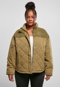Quiltet olivengrønn jakke med faux shearling yoke, høy krage, trykknap- og glidelås-lukking, og oversized passform. Har en glatt tekstur.