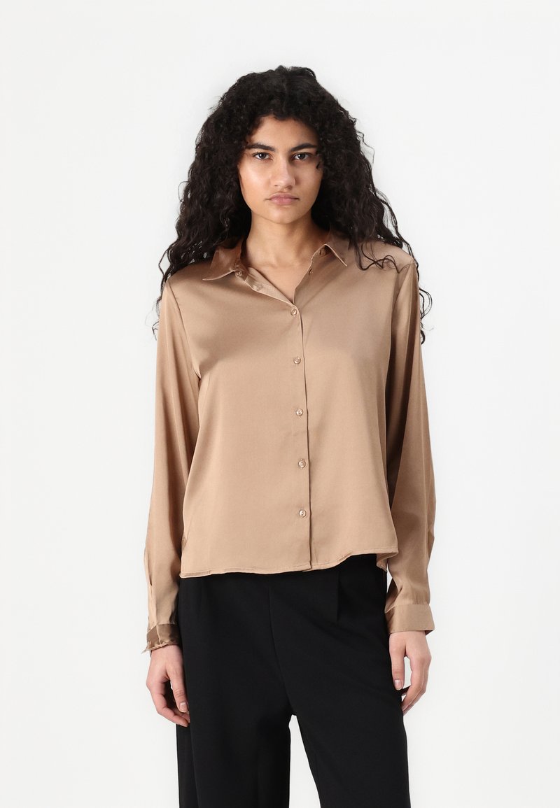 Bruine satijnen blouse met lange mouwen en een knopenlijst aan de voorkant en kraag, met een iets cropped ontwerp en een zachte glanzende textuur.