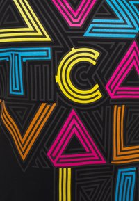 Černá tkanina s výraznými geometrickými vzory v žluté, růžové, modré a oranžové barvě, s vrstvenými obrysy a variabilní tloušťkou linií.