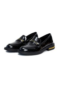 Mocassins en cuir verni noir avec un petit talon, présentant une sangle décorative et des accents de couture jaunes. Texture lisse et brillante sur l'ensemble.