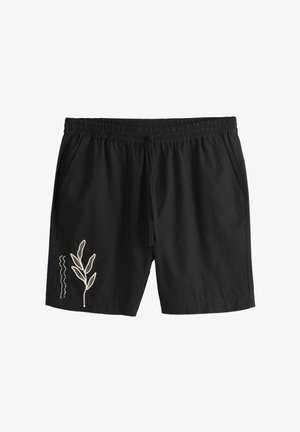 Czarne spodenki z elastyczną talią, bocznymi kieszeniami i białą haftowaną grafiką liścia na lewej nogawce przy krawędzi.