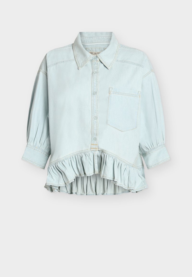 Chemise bleu clair à boutons, manches longues, col, une poche poitrine et ourlet à volants, présentée sur fond blanc.