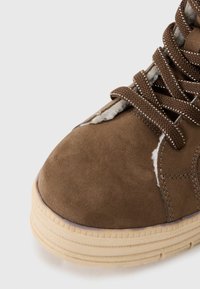 Braune Wildleder-Hochtop-Schuhe mit strukturiertem Obermaterial, beiger Gummisohle und braunen Schnürsenkeln. Verfügt über feine Steppnähte und ein weiches Innenfutter.