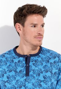 Blau gemustertes Hemd mit floralem Design, Henley-Ausschnitt mit zwei Knöpfen, kurzen Ärmeln und strukturierter Stoffqualität.