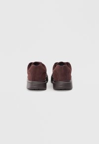 Zapatillas de ante marrón con un acabado texturizado, puntera redondeada y cuello acolchado. Presentan una suela de goma oscura resistente con acentos de logo.