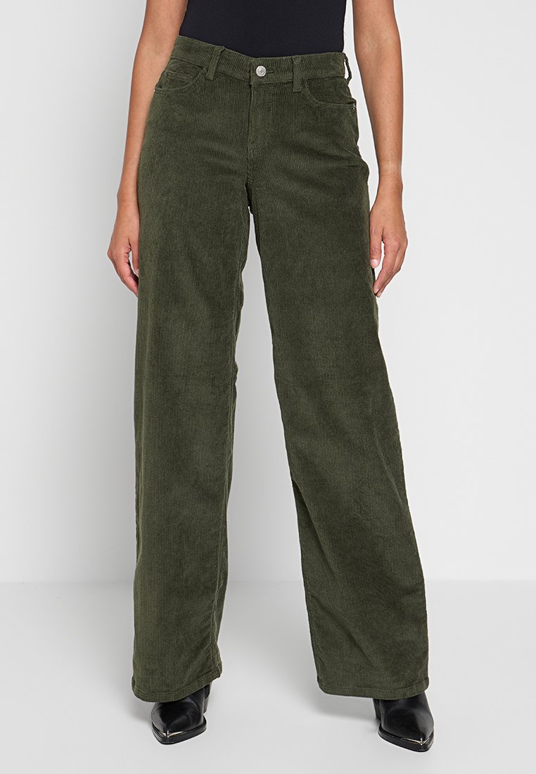 Groene corduroy wijde broek met een gestructureerd oppervlak, voorzien van een knoopsluiting en een vijf-pocket ontwerp, gestyled met een zwarte top en enkellaarsjes.