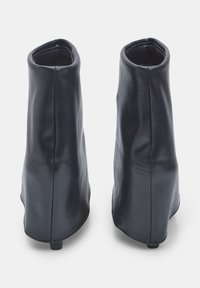 Stivali alla caviglia in pelle nera dal design elegante, con una superficie liscia, punte arrotondate e tacco basso. Nessun hardware o dettaglio visibile.