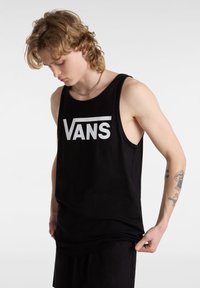 Musta toppi, joka on valmistettu puuvillasta, ja siinä on voimakas valkoinen "VANS"-logo. Hihaton malli, pyöreä kaula-aukko ja väljä istuvuus.