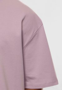 Kortærmet T-shirt i blødt lys lavendelbomuld med afslappet pasform, der har minimal syning og en glat tekstur.